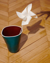 Vase Double Jeu Bleu Sarah/Chocolat et moulin à vent en papier posés sur un parquet en chevrons
