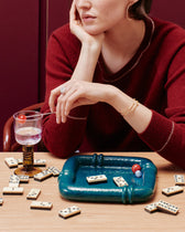 Vide-poche Coco Bleu Sarah et dominos sur table en bois, femme en pull bordeaux accoudée, mur bordeaux